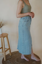 Load image into Gallery viewer, detail view of model wearing the as long as I live denim midi skirt. model has the skirt paired with the used to know bodysuit in the color light moss.