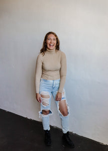 model wearing the can't get enough top in the color oatmeal. model has the top paired with a pair of light wash, distressed denim