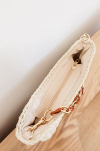 weekend getaway bag in the color cream. bag is shown with the acrylic and chain strap attached.