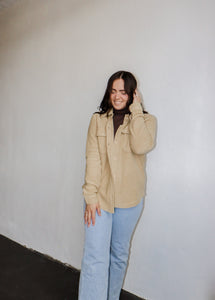 model wearing the right where you left me shacket in the color khaki. model has the shacket paired with the can't get enough top in the color brown and a pair of light wash denim.