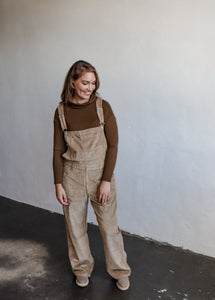model wearing the settlin' down corduroy overalls in the color taupe. model has the overalls paired with the by your side top in the color espresso and a pair of neutral boots.