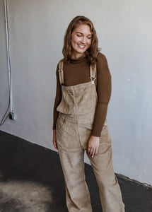 model wearing the settlin' down corduroy overalls in the color taupe. model has the overalls paired with the by your side top in the color espresso.