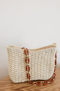 weekend getaway bag in the color cream. bag is shown with the acrylic and chain strap attached.