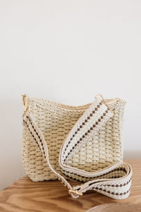 weekend getaway bag in the color cream. bag is shown with the crossbody canvas strap attached.
