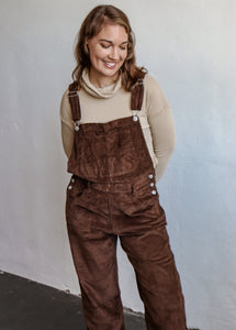 model wearing the settlin' down corduroy overalls in the color brown. model has the overalls paired with the by your side top in the color taupe.