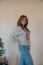 Load image into Gallery viewer, side view of model wearing the holly jolly crewneck sweatshirt. model has the sweatshirt paired with the genevive denim.