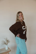 Load image into Gallery viewer, side view of model wearing the ribbons + bows sweater in the color chocolate. model has the sweater paired with the charleston denim.