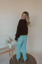 Load image into Gallery viewer, back view of model wearing the ribbons + bows sweater in the color chocolate. model has the sweater paired with the charleston denim.