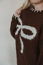 Load image into Gallery viewer, detail view of model wearing the ribbons + bows sweater in the color chocolate. model has the sweater paired with the charleston denim.