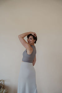 side view of model wearing the long live skirt in the color champagne. model has the skirt paired with the forever yours top in the color smoky taupe. 