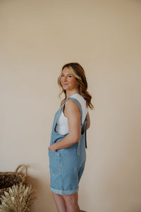 side view of model wearing the carly denim romper. model has the romper paired with the forever yours top in the color white.
