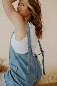 detail view of model wearing the carly denim romper. model has the romper paired with the forever yours top in the color white.