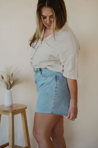 side view of model wearing the dakota denim shorts. model has the shorts paired with the out of office top in the color taupe.