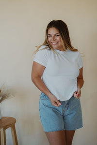 front view of model wearing the back to the basics tee in the color white. model has the top paired with the dakota denim shorts.