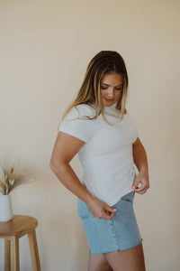 side view of model wearing the back to the basics tee in the color white. model has the top paired with the dakota denim shorts.