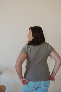 back view of model wearing the back to the basics tee in the color olive. model has the top paired with the charleston denim.