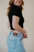 Load image into Gallery viewer, close-up side view of model wearing the charleston denim. model has the denim paired with the never hesitate top in the color black.