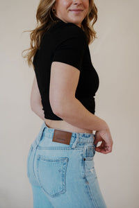 close-up side view of model wearing the charleston denim. model has the denim paired with the never hesitate top in the color black.
