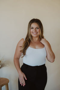 front view of model wearing the used to know bodysuit in the color white. model has the bodysuit paired with the addison denim in the color fade black.
