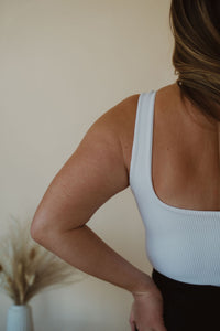 detail view of model wearing the used to know bodysuit in the color white. model has the bodysuit paired with the addison denim in the color fade black.