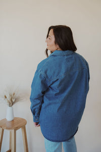 back view of model wearing the denim daze top. model has the top paired with the change your mind bodysuit in the color white and the charleston denim.