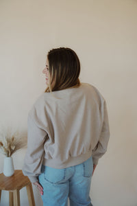 back view of model wearing the winding roads bomber jacket in the color light taupe. model has the jacket paired with the used to know bodysuit in the color biscuit and the charleston denim.