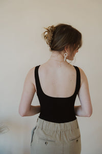 back view of model wearing the used to know bodysuit in the color black. model has the bodysuit paired with the in another life skirt.