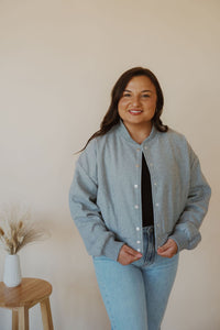 front view of model wearing the winding roads bomber jacket in the color light grey. model has the jacket paired with the change your mind bodysuit in the color black and the charleston denim.