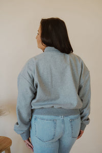 back view of model wearing the winding roads bomber jacket in the color light grey. model has the jacket paired with the change your mind bodysuit in the color black and the charleston denim.
