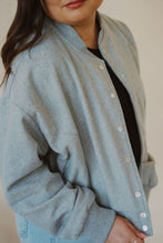 Load image into Gallery viewer, detail view of model wearing the winding roads bomber jacket in the color light grey. model has the jacket paired with the change your mind bodysuit in the color black and the charleston denim.
