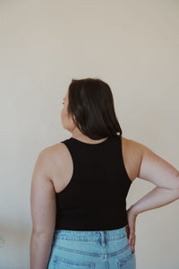 back view of model wearing the change your mind bodysuit in the color black. model has the bodysuit paired with the charleston denim.