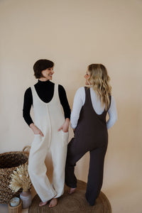 models wearing the never let me go jumpsuit in the colors cream and chocolate. models have the jumpsuits paired with the all along tops in the colors black and white.