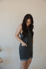 Load image into Gallery viewer, side view of model wearing the carly denim romper in the color charcoal. model has the romper paired with the these days top in the color charcoal.