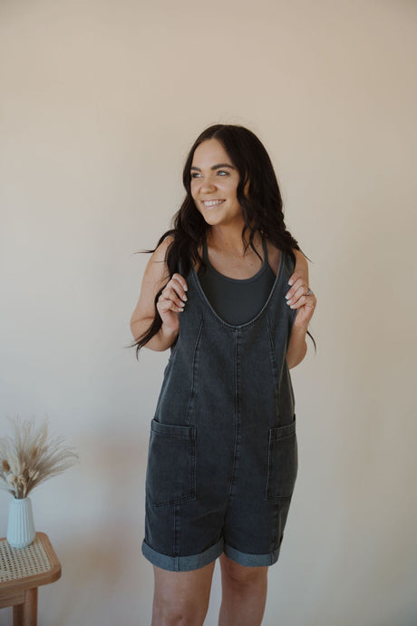 front view of model wearing the carly denim romper in the color charcoal. model has the romper paired with the these days top in the color charcoal.