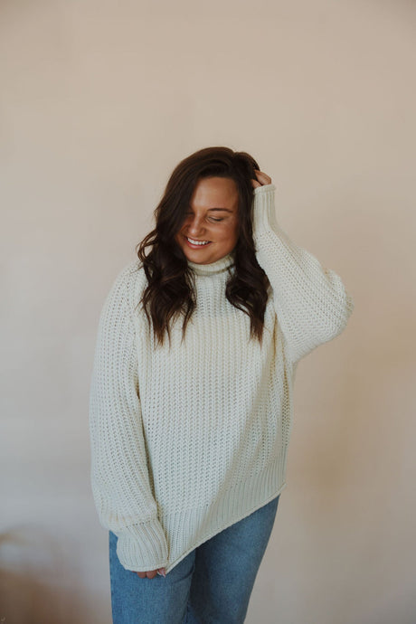 front view of model wearing the patiently waiting sweater in the color ivory. model has the sweater paired with the aurora denim.