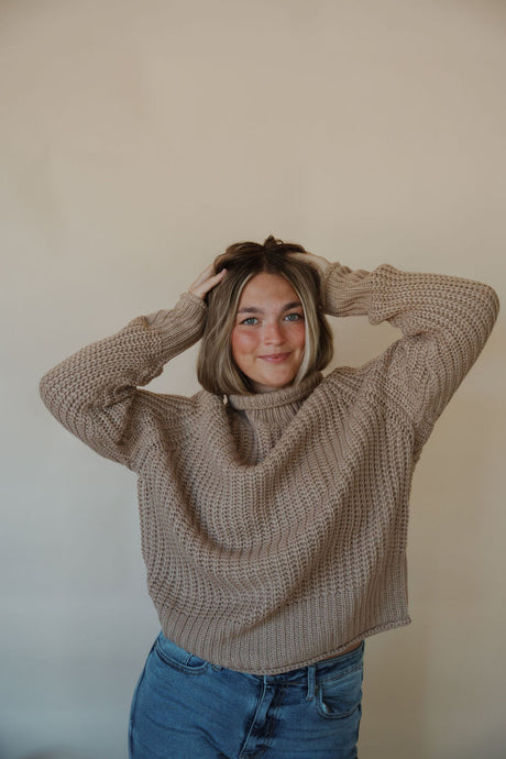 front view of model wearing the patiently waiting sweater in the color oat. model has the sweater paired with the aurora denim.