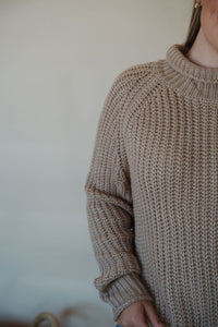 detail view of model wearing the patiently waiting sweater in the color oat. model has the sweater paired with the aurora denim.