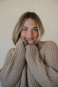 detail view of model wearing the patiently waiting sweater in the color oat. model has the sweater paired with the aurora denim.