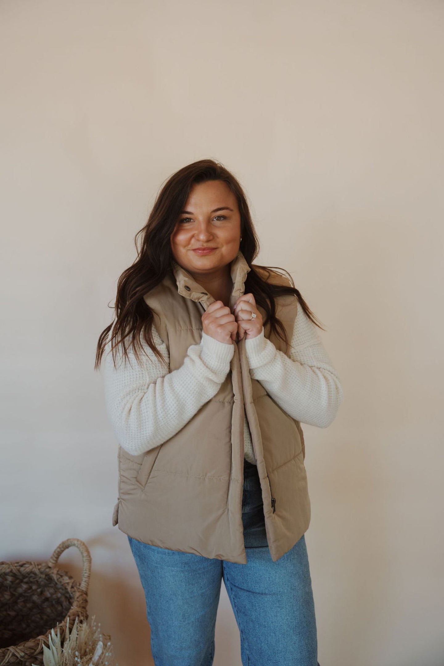 front view of model wearing the long way home puffer vest in the color mocha. model has the vest paired with the play it cool sweater and the aurora denim.