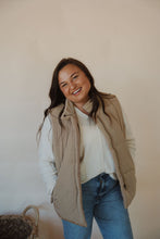 Load image into Gallery viewer, front view of model wearing the long way home puffer vest in the color mocha. model has the vest paired with the play it cool sweater and the aurora denim.