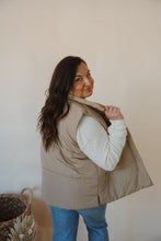 Load image into Gallery viewer, side view of model wearing the long way home puffer vest in the color mocha. model has the vest paired with the play it cool sweater and the aurora denim.