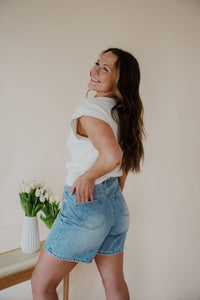 side view of model wearing the austin denim shorts. model has the shorts paired with the look after you sweater vest.