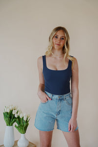 front view of model wearing the used to know bodysuit in the color navy. model has the top paired with the dakota denim shorts and the dainty mallory necklace.