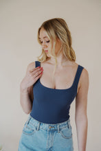 Load image into Gallery viewer, close front view of model wearing the used to know bodysuit in the color navy. model has the top paired with the dakota denim shorts and the dainty mallory necklace.