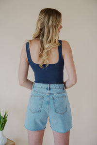 back view of model wearing the dakota denim shorts. model has the shorts paired with the used to know bodysuit in the color navy and the dainty mallory necklace.