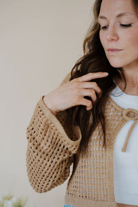 detail view of model wearing the ocean avenue cardigan in the color taupe. model has the cardigan paired with the forever yours top in the color white and the austin denim shorts.