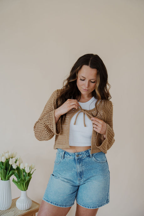 front view of model wearing the ocean avenue cardigan in the color taupe. model has the cardigan paired with the forever yours top in the color white and the austin denim shorts.