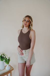 front view of model wearing the change your mind bodysuit in the color walnut. model has the top paired with the parker shorts and the dainty mallory necklace.