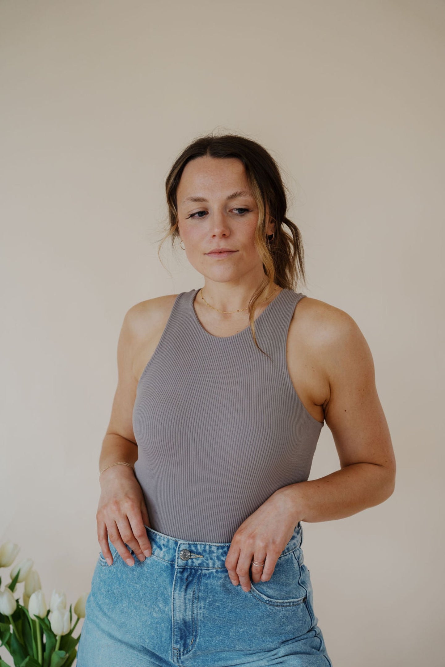 front view of model wearing the change your mind bodysuit in the color smoky taupe. model has the top paired with the austin denim shorts and the anna necklace.