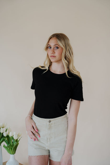 front view of model wearing the take a chance bodysuit in the color black. model has the top paired with the parker shorts and the dainty mallory necklace.